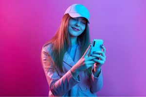 portrait-young-beautiful-fashionable-model-wearing-leather-baker-baseball-cap-holding-smart-phone-hands 1